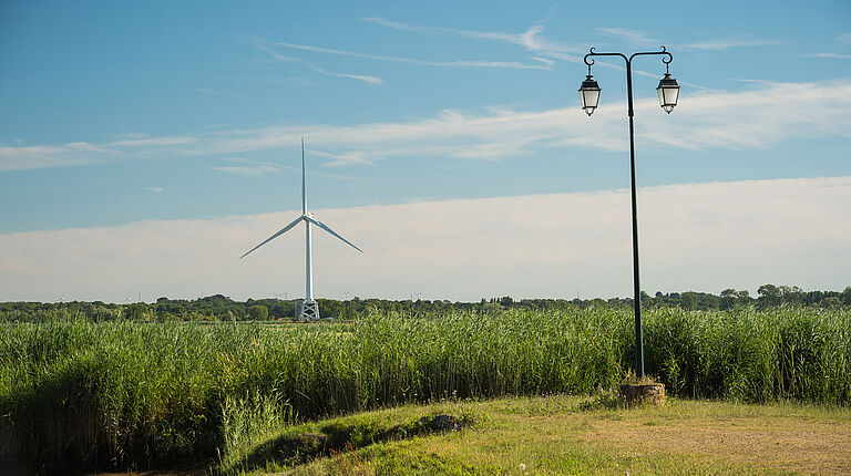 lampadaire et éolienne en premier plan avec de nombreuses autres éoliennes en fond de paysage