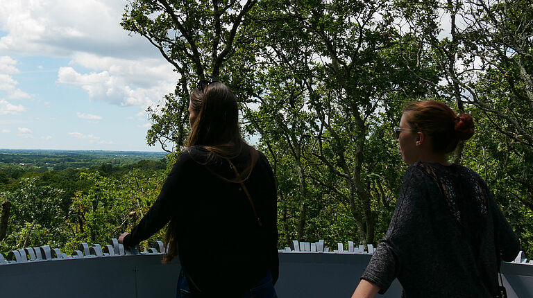 deux jeunes femmes profitent de la vue panoramique depuis le sommet du nid dont on aperçoit l'arrondi et la stucture metallique