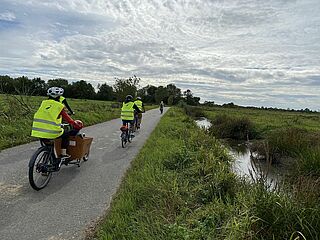 une famille se balade à vélo et vélocargo le long d'un petit canal